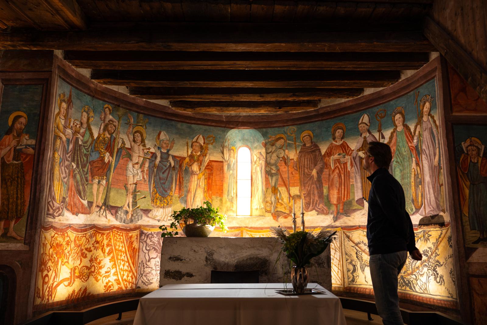 Bezoeker bekijkt middeleeuwse fresco’s in een Alpenkerk in Oostenrijk.