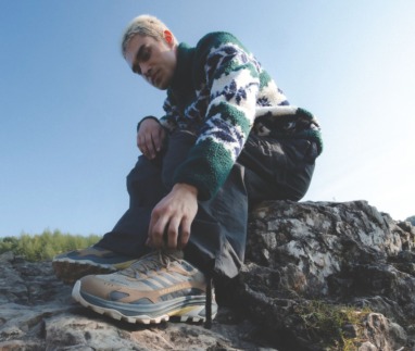 Man strikt zijn wandelschoenen van Merrell op een rotsachtig pad in de Ardennen