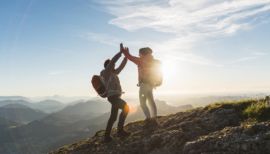 Vrolijk stel geeft elkaar een high five bovenop een berg