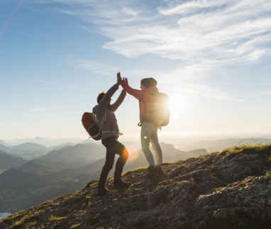 Vrolijk stel geeft elkaar een high five bovenop een berg