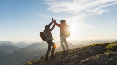 Vrolijk stel geeft elkaar een high five bovenop een berg