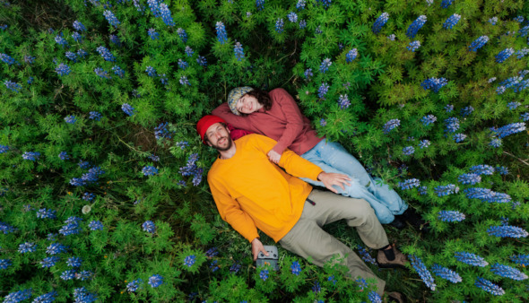 Man en vrouw liggen tussen de bloemen in IJsland, het vreedzaamste land ter wereld in 2026