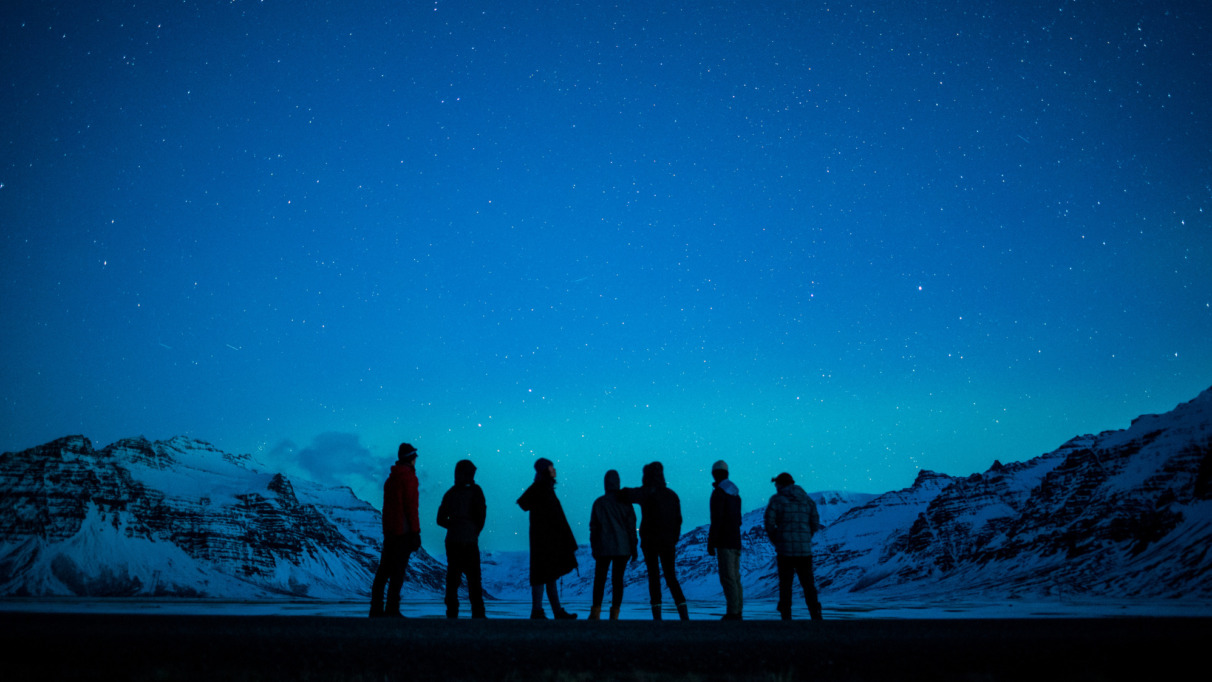 Een groep mensen kijkt naar het noorderlicht in Zuid-Ijsland