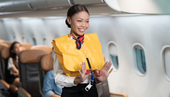 Stewardess toont veiligheidsinstructies aan boord van vliegtuig
