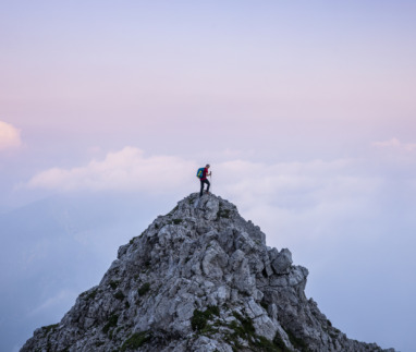 hiker op bergtop tijdens zosondergang