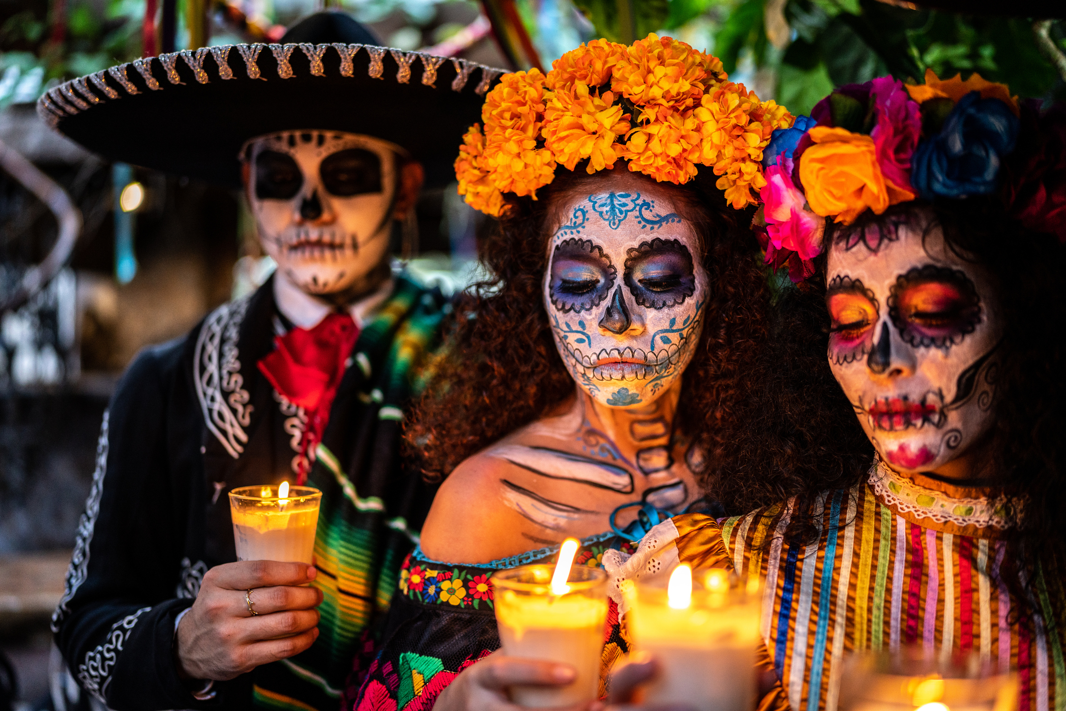 Mensen met kleurrijke schedelmake-up en kaarsen tijdens Día de los Muertos in Mexico.