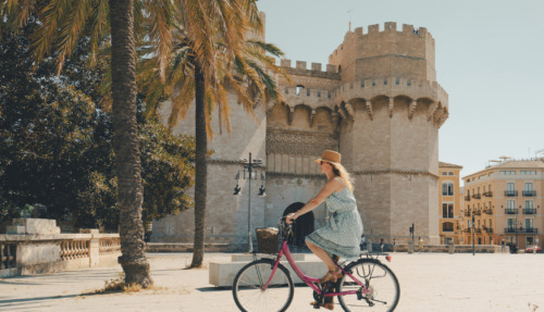 Vrouw fietst langs de Torres de Serranos-poort in Valencia, Spanje