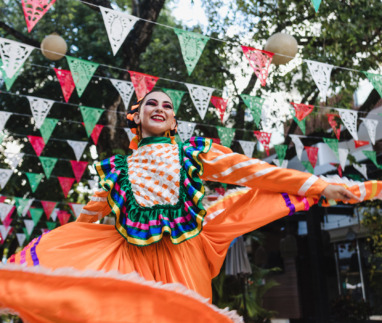Mexicaanse vrouw in traditionele kleding danst onder vlaggen voor Cinco de Mayo