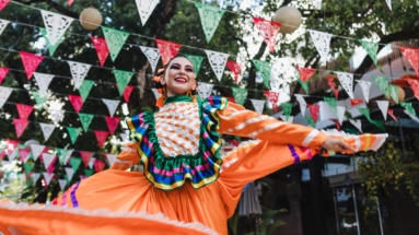 Mexicaanse vrouw in traditionele kleding danst onder vlaggen voor Cinco de Mayo