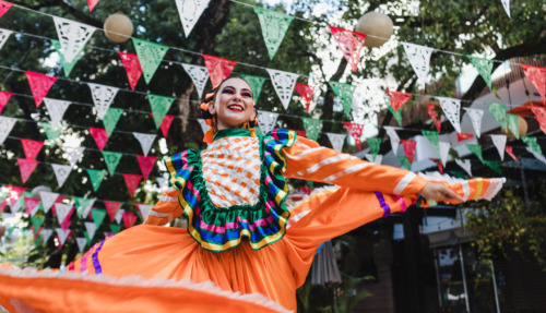 Mexicaanse vrouw in traditionele kleding danst onder vlaggen voor Cinco de Mayo