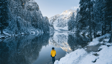 Man kijkt uit over meer en bergen in een besneeuwd winterlandschap