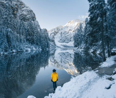 Man kijkt uit over meer en bergen in een besneeuwd winterlandschap