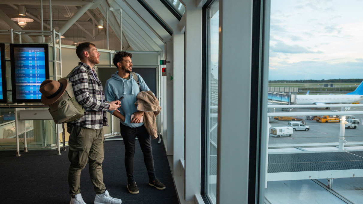 Twee vrienden kijken door het raam uit over Dusseldorf Airport