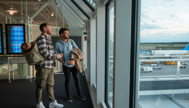 Twee vrienden kijken door het raam uit over Dusseldorf Airport