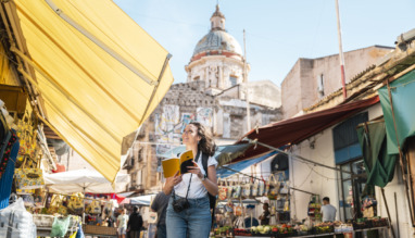 Vrolijke toeriste wandelt door Palermo, Sicilië met een reisgids in de hand