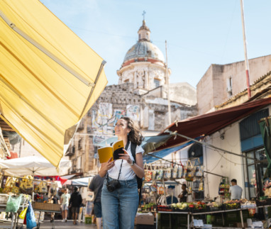 Vrolijke toeriste wandelt door Palermo, Sicilië met een reisgids in de hand