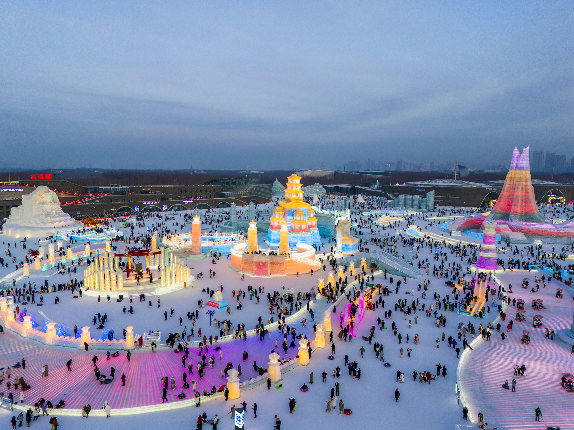 Bezoekers wandelen tussen kleurrijk verlichte ijs- en sneeuwsculpturen op winterfestival in China.