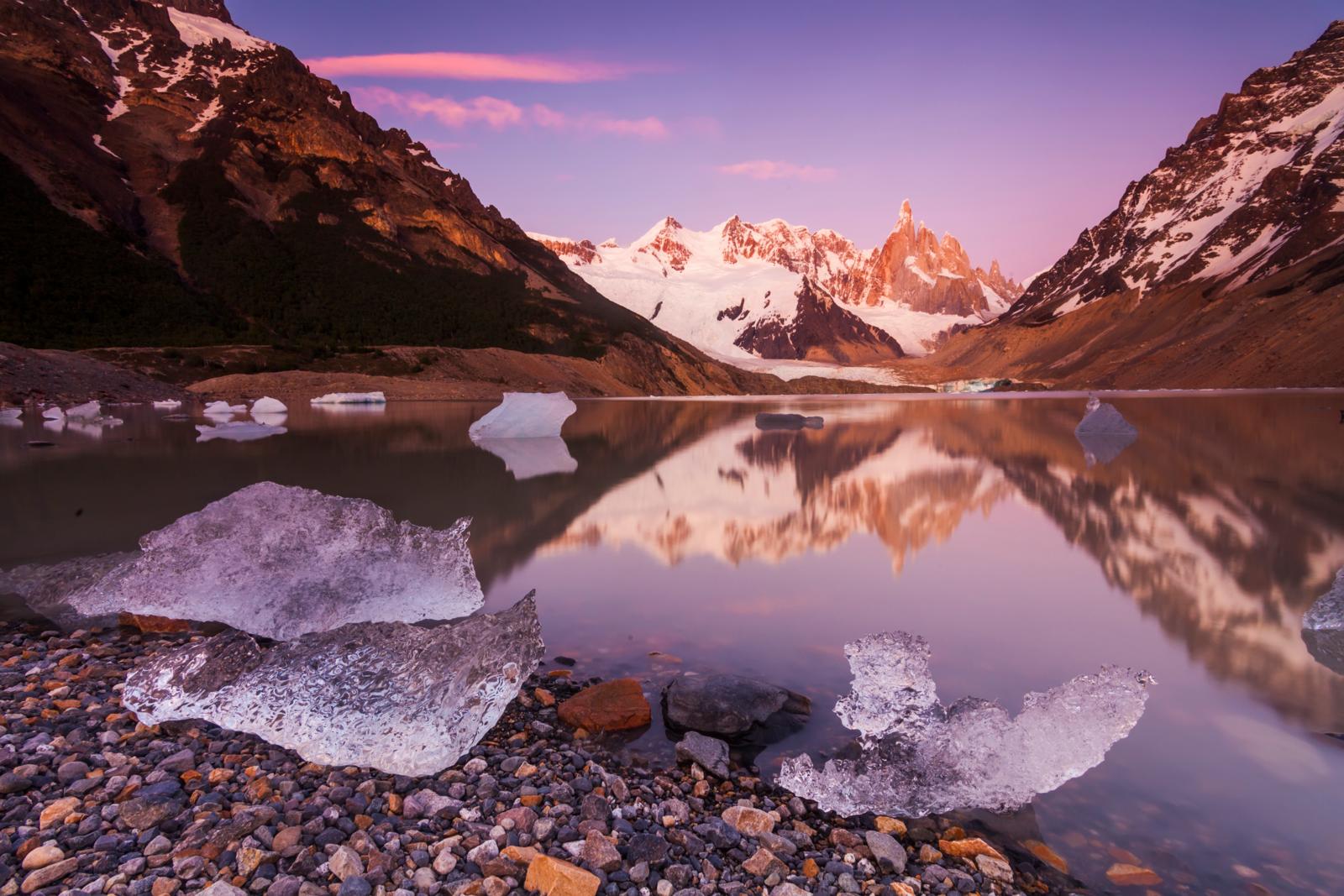 Ijsschotsen drijven in een stille gletsjerlagune met besneeuwde bergen in Patagonië.