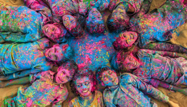 Groep vrolijke Indiase kinderen liggend in een kring tijdens Holi Festival in India