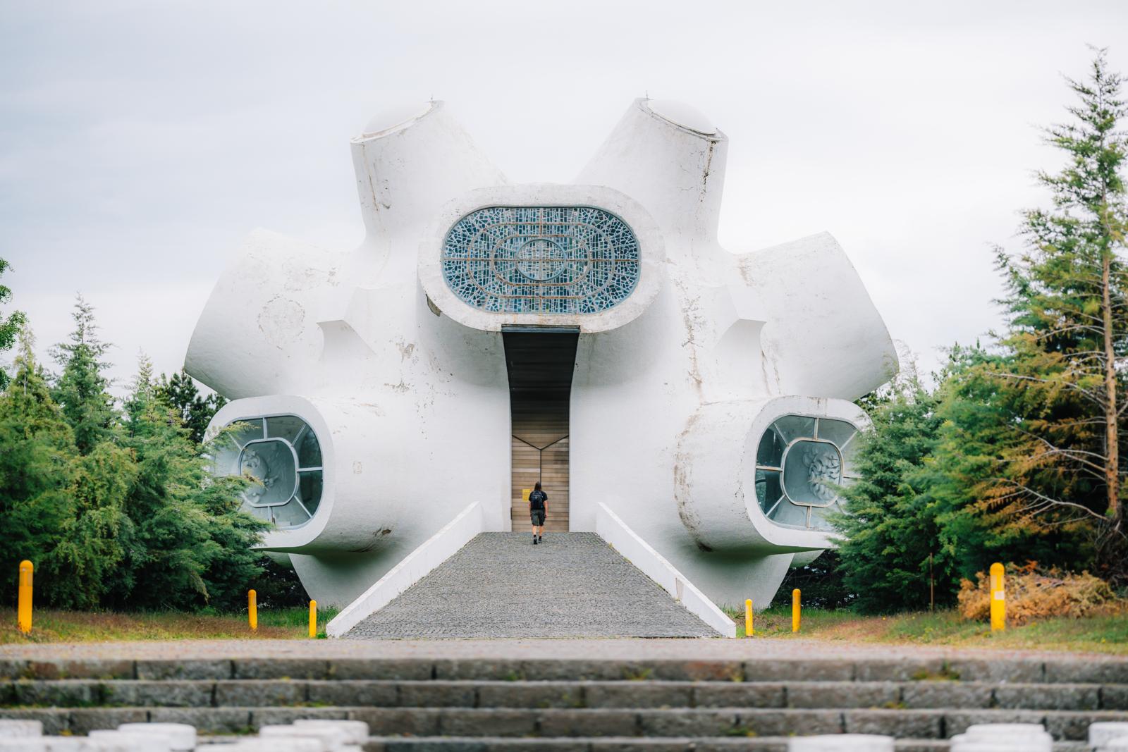 Het futuristische Ilindenmonument in Kruševo, Noord-Macedonië, omringd door bos en gezien vanaf de centrale toegangsweg