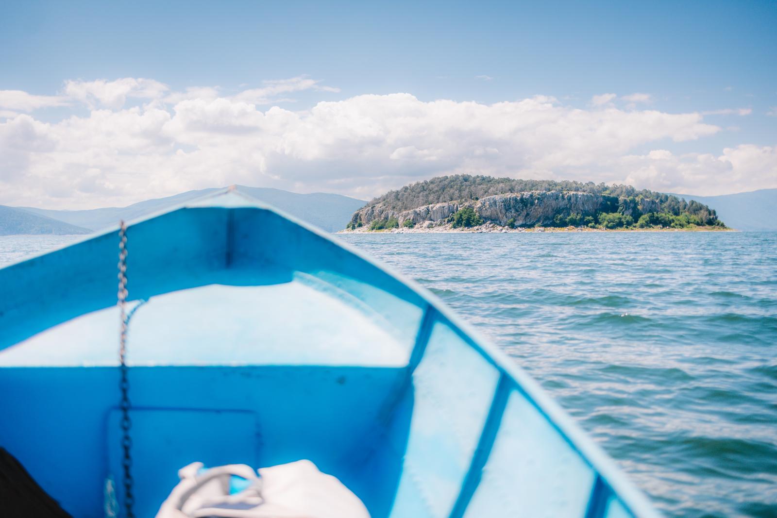 Uitzicht vanaf een blauwe boot op het eiland Golem Grad in het Prespameer in Noord-Macedonië