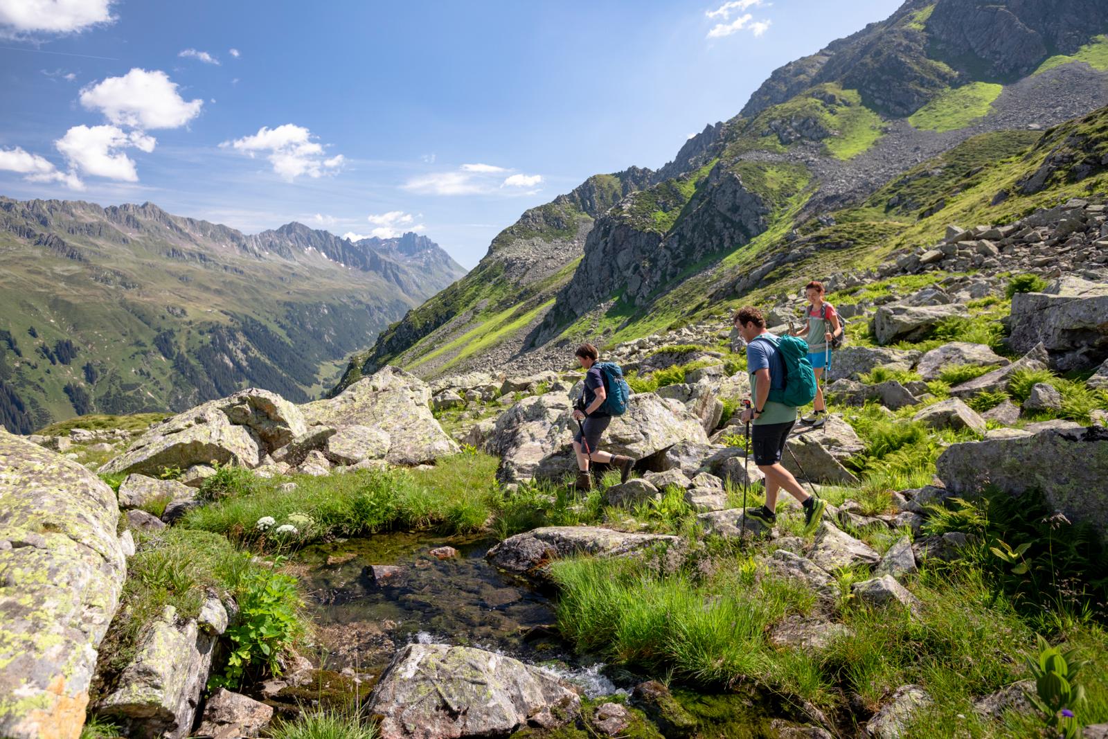 Wandelaars steken een bergbeek over in rotsachtig hooggebergte in het Montafon.