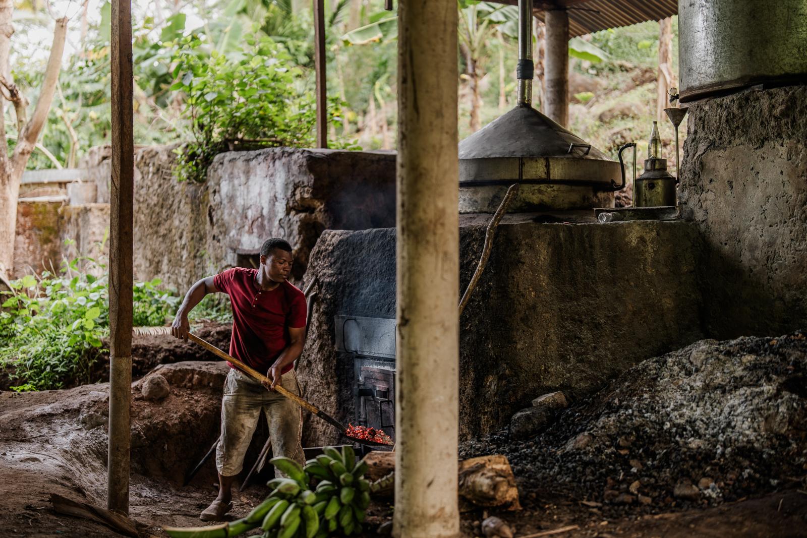 Man bij traditionele destillatieoven voor ylang-ylang op Mohéli in de Comoren