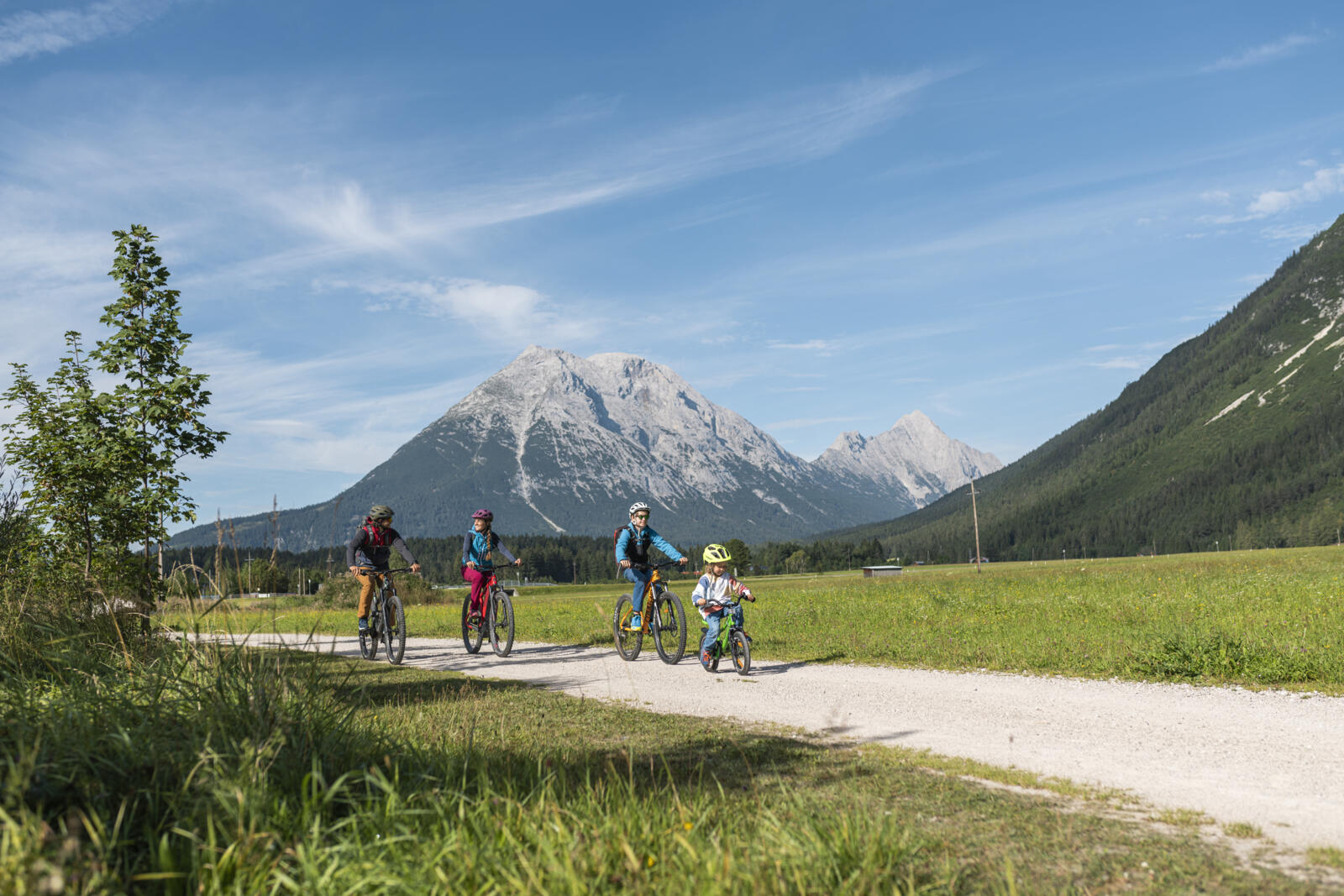 Gezin dat fietst over een grindpad in Leutasch met uitzicht op de bergen van de regio Seefeld in Tirol.