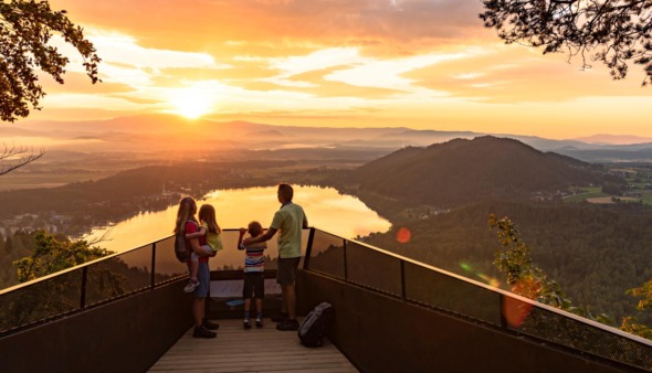 Gezin kijkt uit over de Klopeiner See in Karinthië, Oostenrijk tijdens zonsondergang