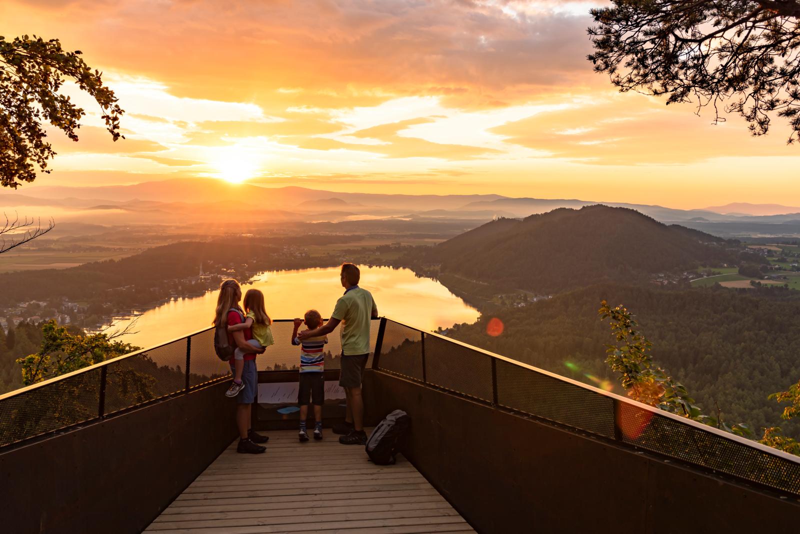 Gezin kijkt uit over de Klopeiner See in Karinthië, Oostenrijk tijdens zonsondergang