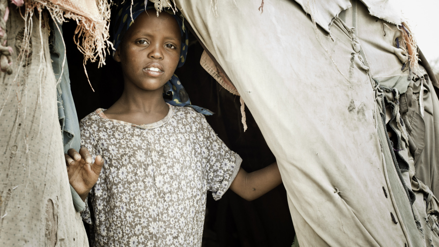 Afrikaans meisje staat in de ingang van haar tent in een kampement in Somalië