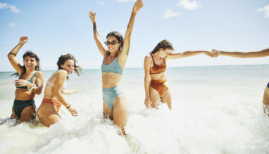 Vrolijke vriendinnen spelen in de branding van de zee in de zomer