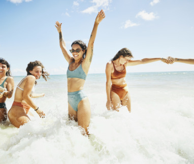 Vrolijke vriendinnen spelen in de branding van de zee in de zomer