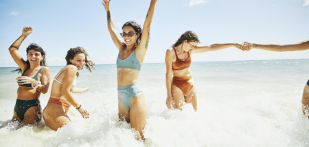 Vrolijke vriendinnen spelen in de branding van de zee in de zomer
