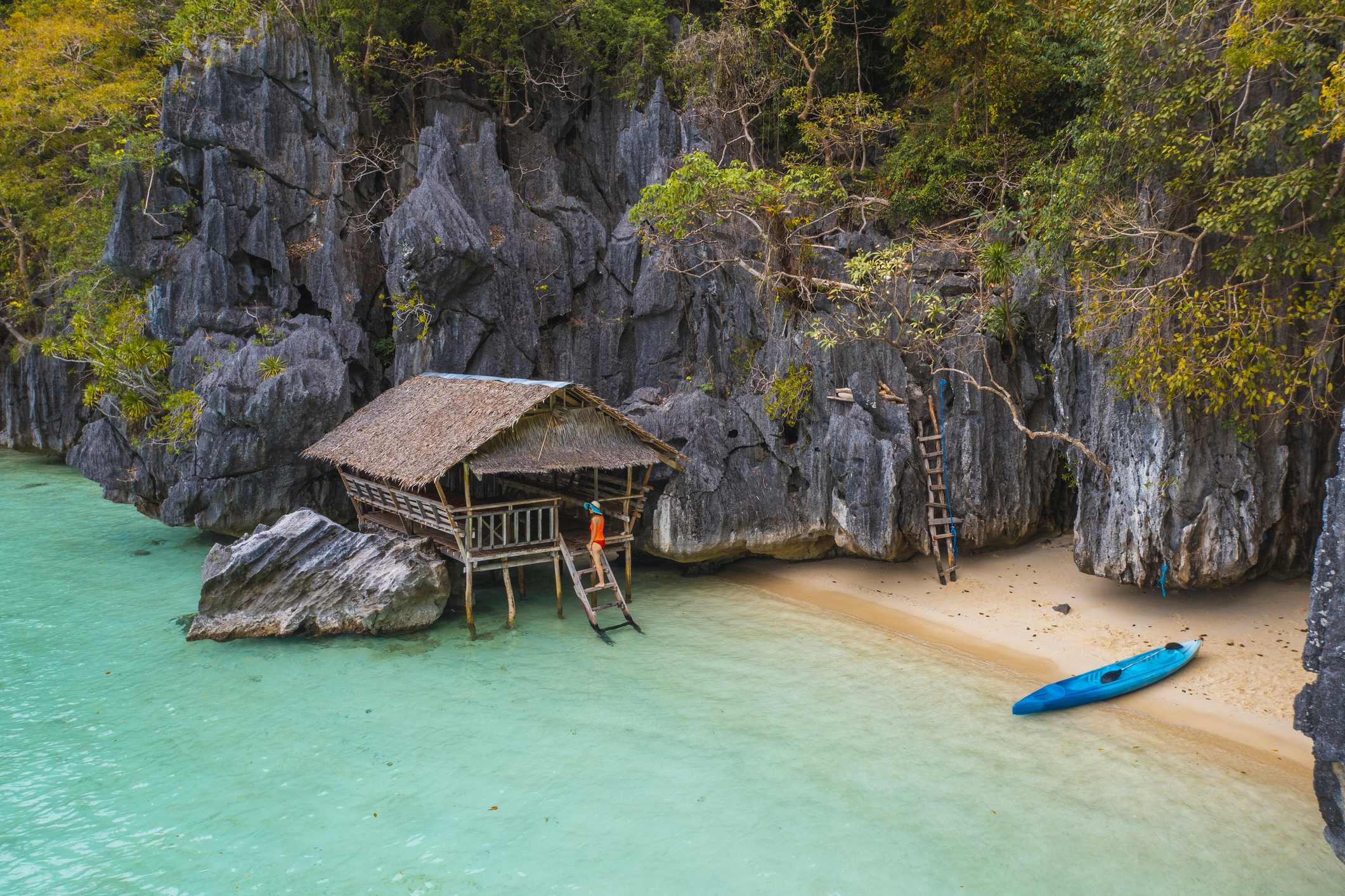 Toeriste bezoekt hutje op het water nabij verscholen strand met kajak in de Filipijnen