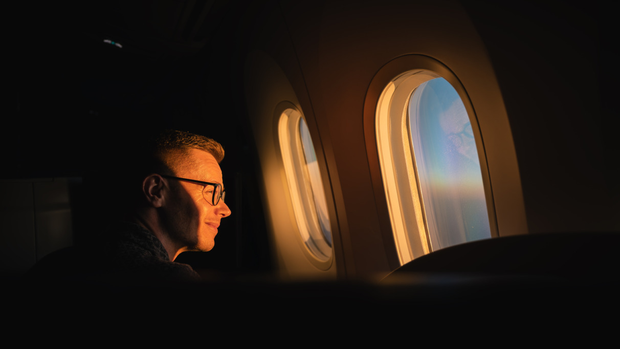 Passagier kijkt naar zonsopkomst door het raam van het vliegtuig