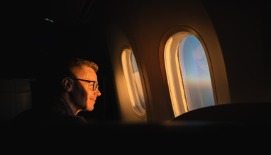 Passagier kijkt naar zonsopkomst door het raam van het vliegtuig