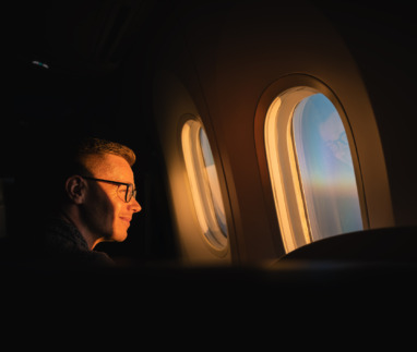 Passagier kijkt naar zonsopkomst door het raam van het vliegtuig