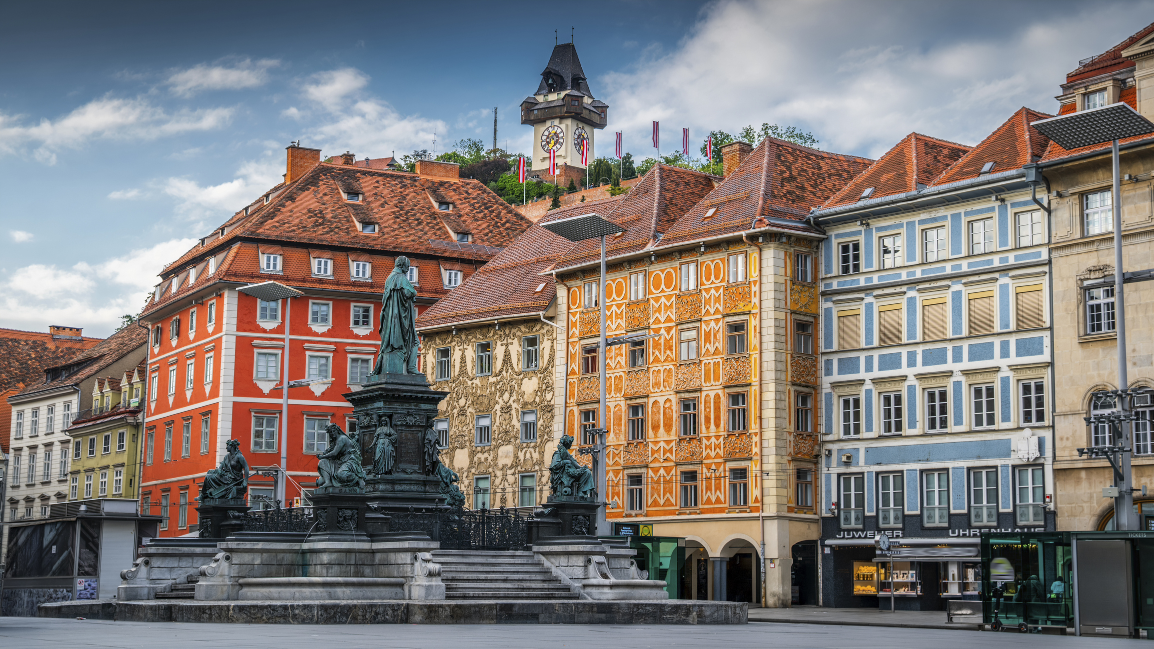 Kleurrijke gebouwen en de Erzherzorg Johann Fontein en Schlossberg klokkentoren achter de Hauptplatz in Graz, Oostenrijk