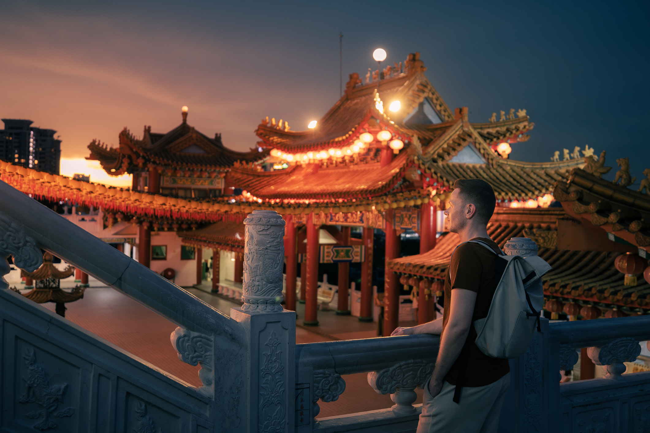 Mannelijke toerist bewondert verlichte Thean Hou Tempel in Kuala Lumpur, Maleisië in de avond