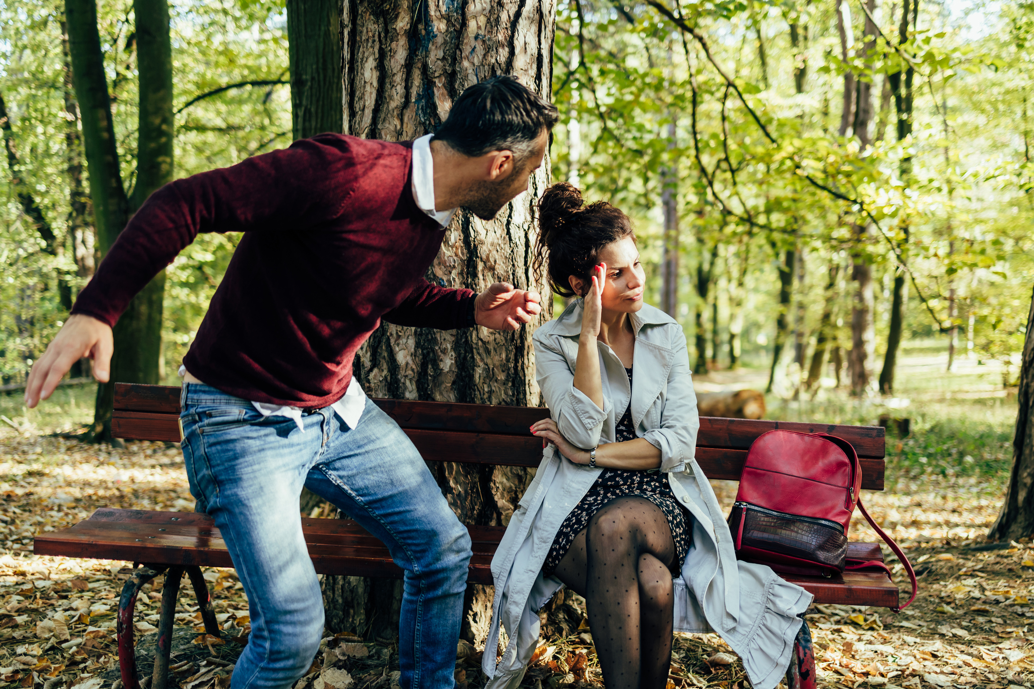 Man in ruziënd stel wil vrouw slaan die op een bankje zit in het park