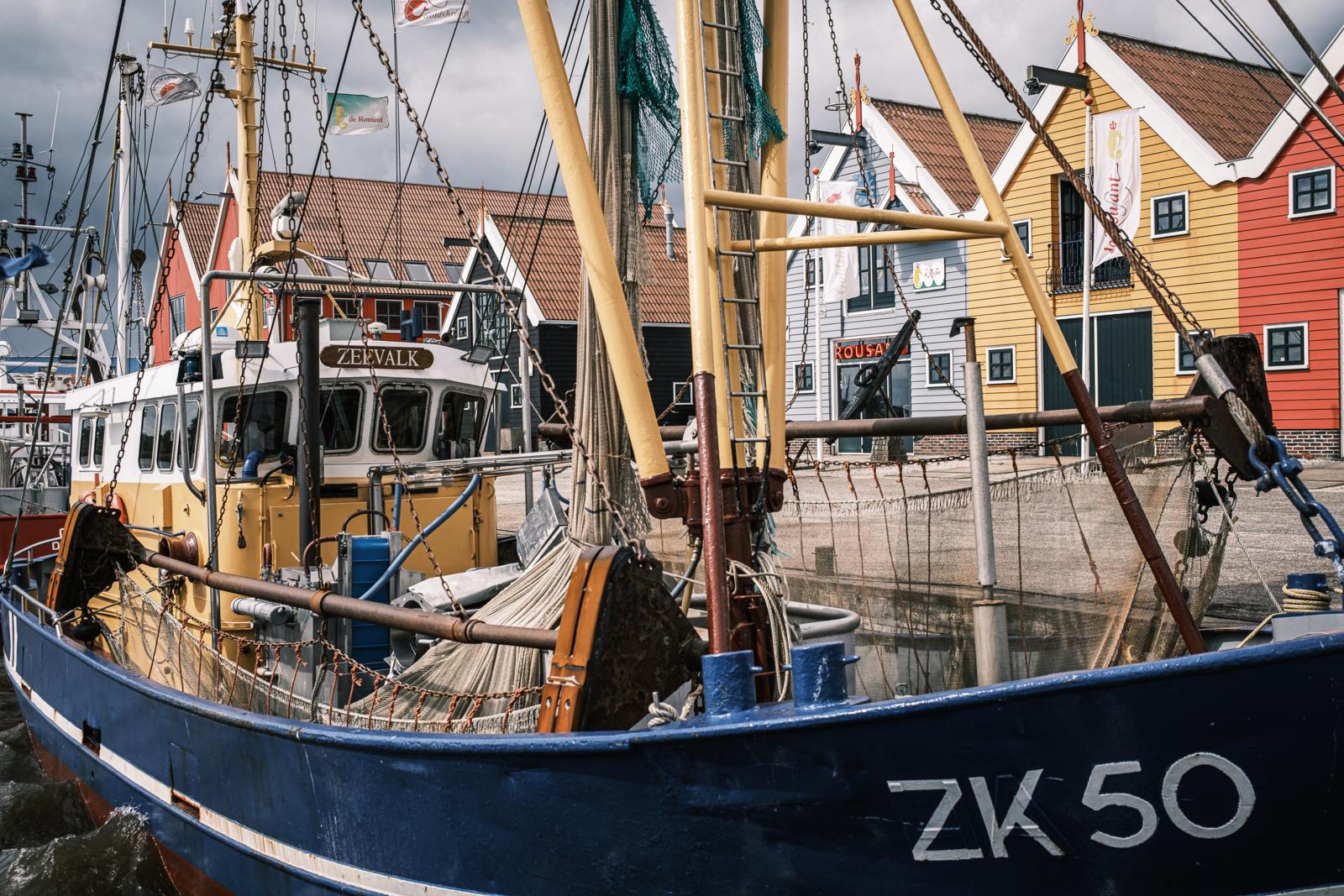 Vissersboot in de haven van Zoutkamp met kleurrijke huizen op de achtergrond.