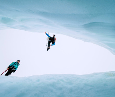 Twee hikers springen over gat in glacier