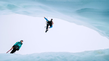 Twee hikers springen over gat in glacier