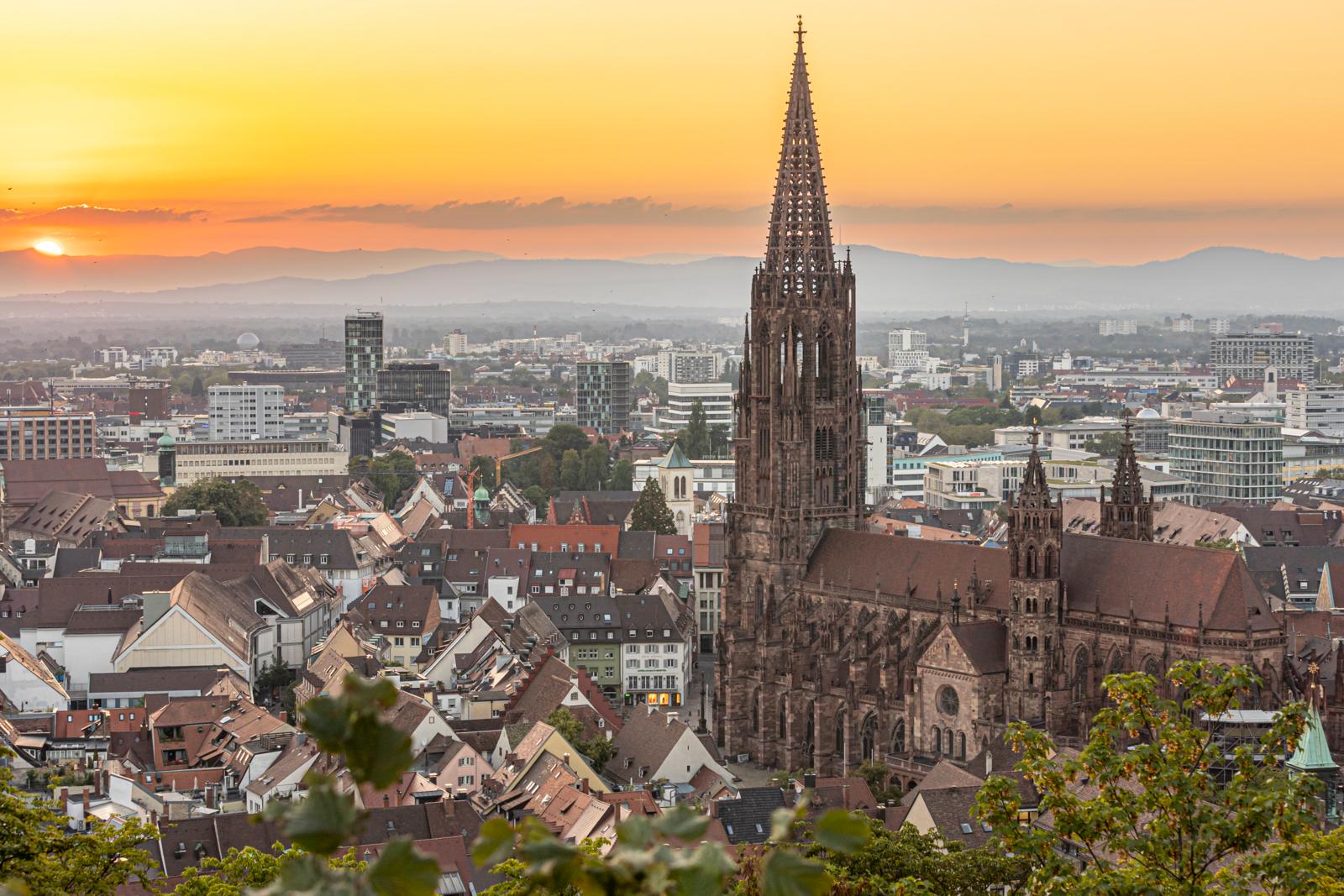 Skyline van Freiburg im Breisgau met de Freiburger Münster en zonsondergang op de achtergrond.