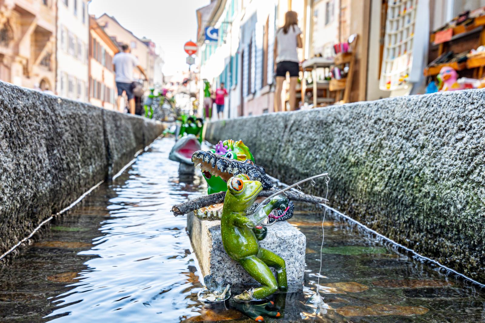 Bächle in Freiburg met kleine speelgoedfiguren in het water tussen de straat.