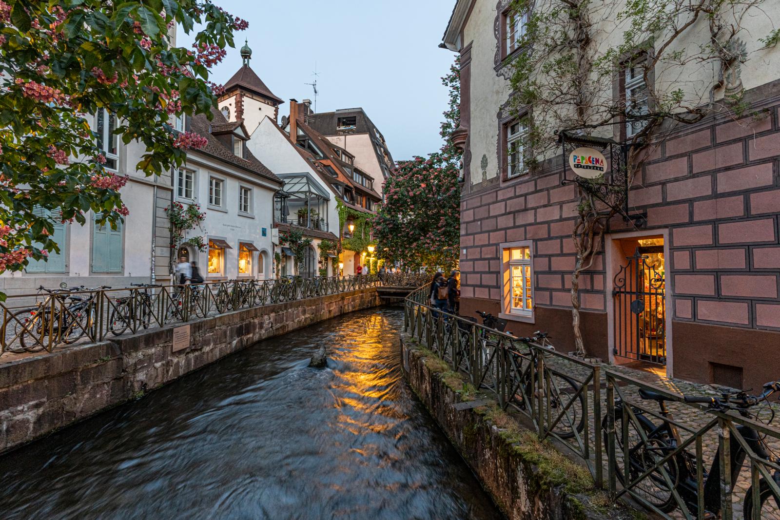 Gerberau in Freiburg met kanaal, historische huizen en avondlicht in de straat.