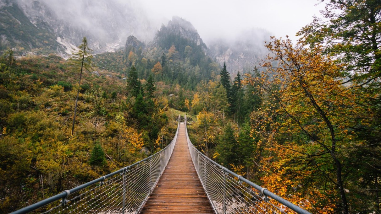 Houten hangbrug over het Klausbachtal in Berchtesgaden met herfstbos en mistige bergen