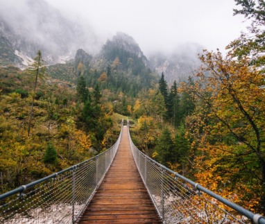 Houten hangbrug over het Klausbachtal in Berchtesgaden met herfstbos en mistige bergen