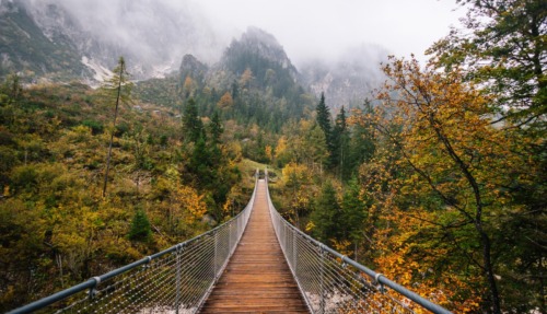 Houten hangbrug over het Klausbachtal in Berchtesgaden met herfstbos en mistige bergen